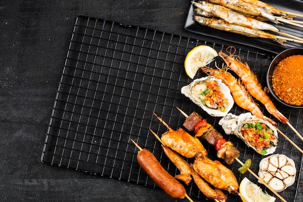 Various barbecue delicacies are placed on the black wood background