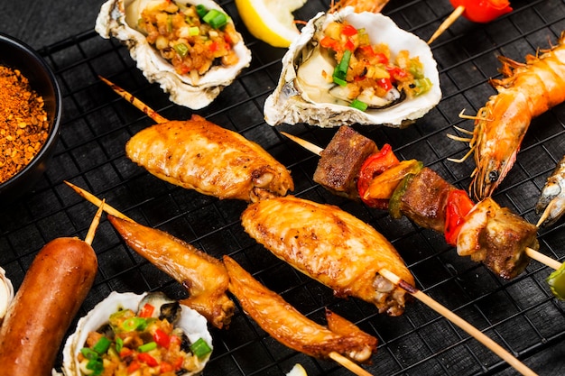 Various barbecue delicacies are placed on the black wood background