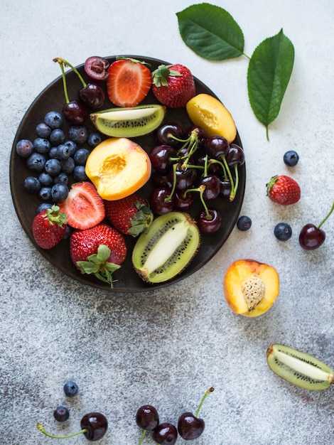 Various berries and fruits on a wooden plate 