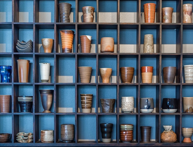 Various ceramic mugs on wooden shelf