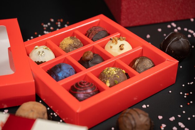 Photo various chocolate truffle candies in a box on gray stone background