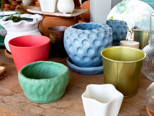 Various colorful ceramic plant pots on wooden table in the shop. Empty diy geometric ceramic planter.