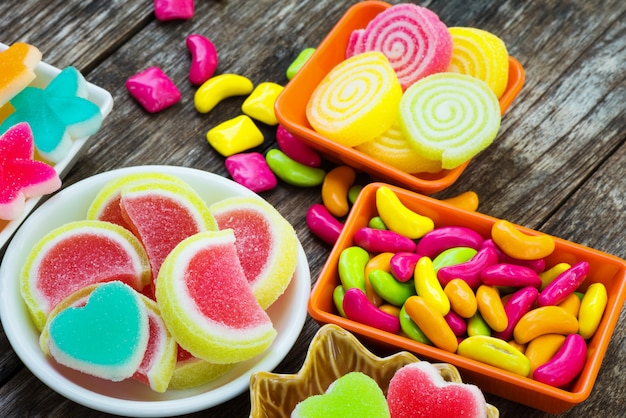 Various colorful sugary candy in container on old wooden plank