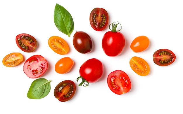 Various colorful tomatoes and basil leaves isolated on white background.