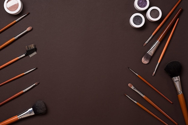 Various cosmetics and brushes on brown background