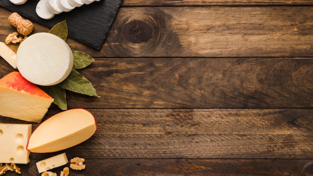 Various delicious cheese with bay leaves and walnut on wooden textured