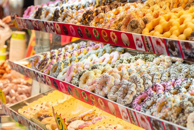 Various of donuts on shelves at street food market.