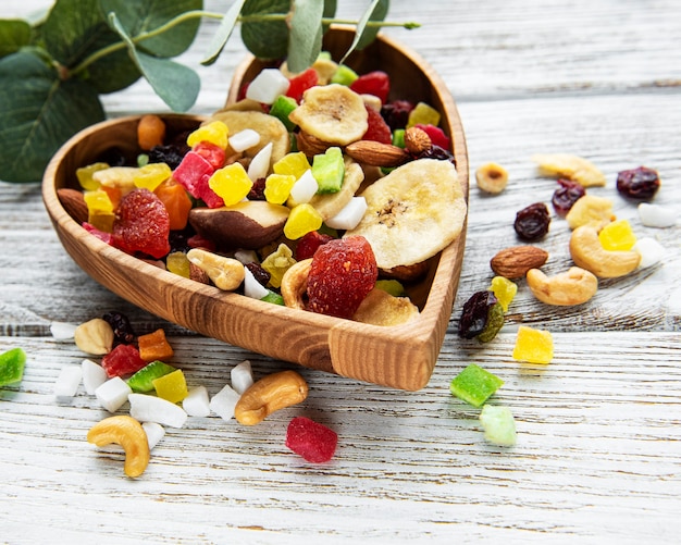 Various dried fruits and mix nuts on a white wooden background.