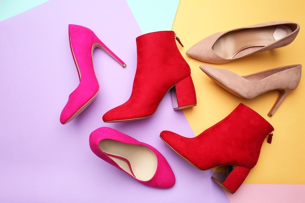 Various female stylish shoes on color background