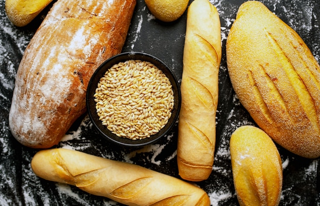 Various fresh bread and buns on a stone table.