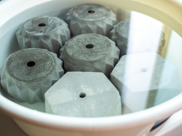 Various geometric concrete planters in white plastic basin with water