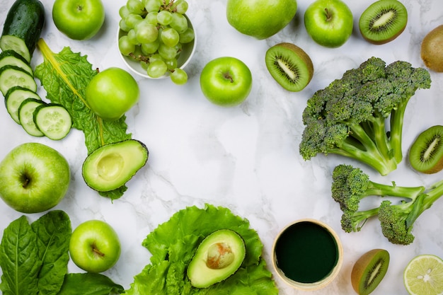 Various green fruits and vegetables on marble