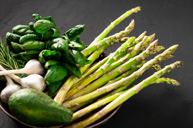 Various green vegetables on a dark background Asparagus spinach avocado garlic Vegetarian food concept