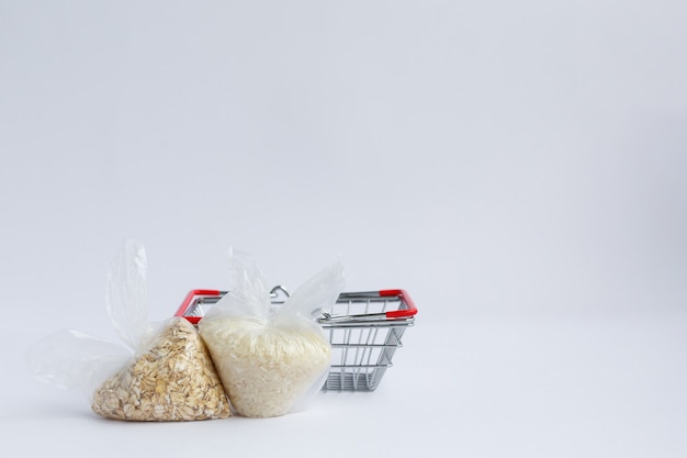 Various groats in packages near grocery basket Rice and oatmeal