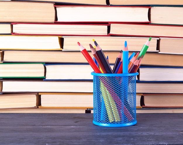  various hardback books and blue stationery glass with multi colored wooden pencils