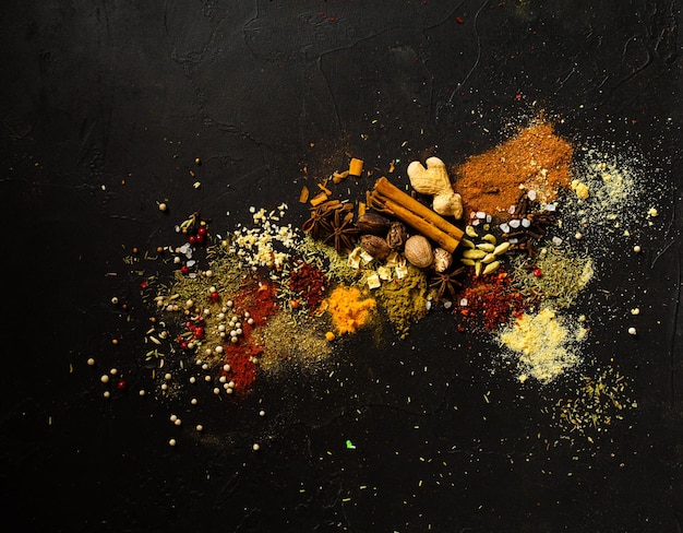 Various herbs and spices on black stone plate, art composition.