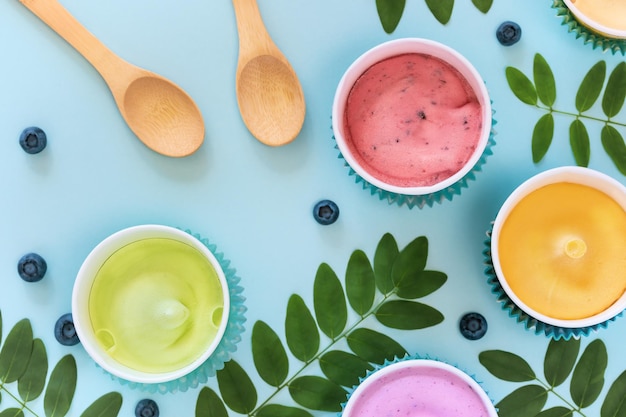 Various homemade vegan fruit ice creams with leaves blueberries and wooden spoons on a blue background