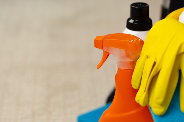 Various household cleaning detergents and bottles in a plastic bucket on the floor