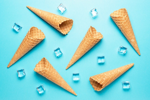 Various ice cream cones with ice cubes on blue background