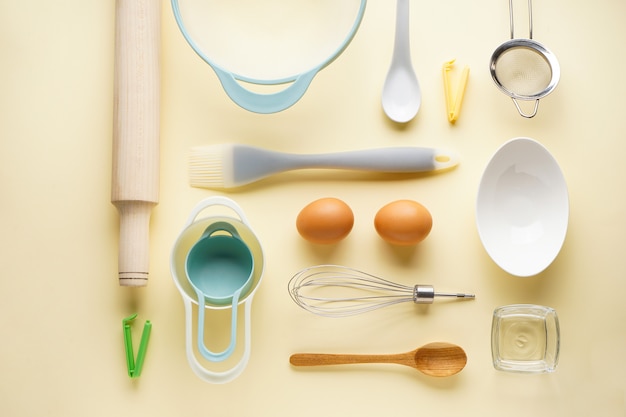 Various kitchen utensils on a yellow background, top view.