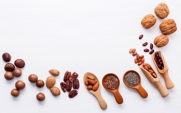 Various legumes and different kinds of nuts set up on white wooden table.