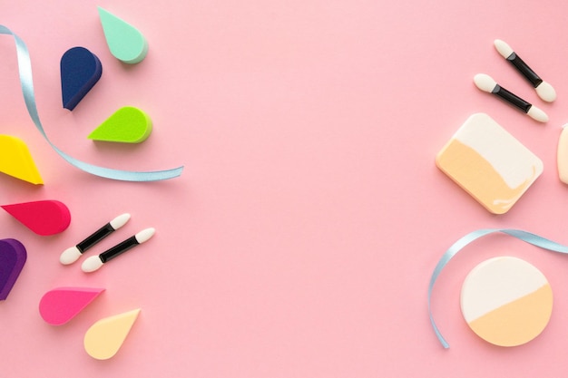 Various makeup sponges and eyeshadow applicators on pink background copyspace