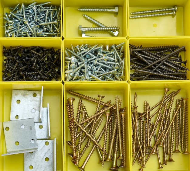 Various metal screws in separate yellow plastic containers