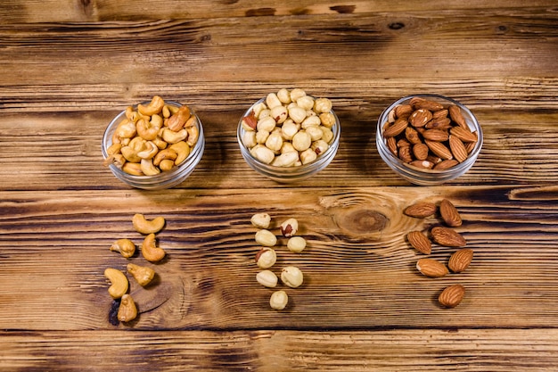 Various nuts almond cashew hazelnut in glass bowls on a wooden table Vegetarian meal Healthy eating concept