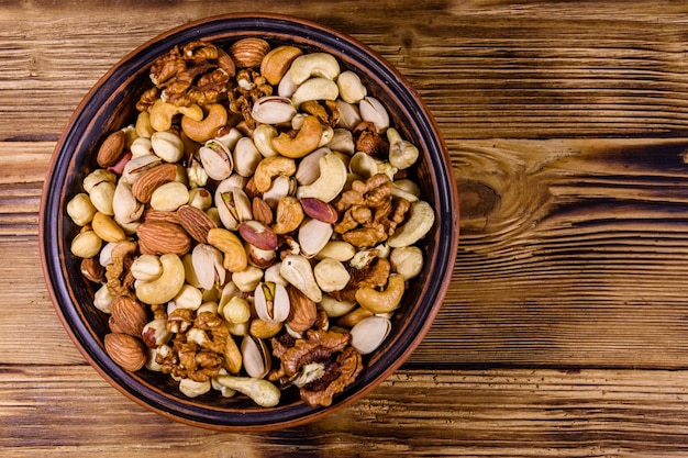 Various nuts almond cashew hazelnut pistachio walnut in ceramic plate on a wooden table Vegetarian meal Healthy eating concept Top view