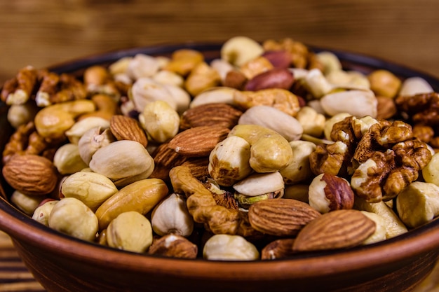 Various nuts (almond, cashew, hazelnut, pistachio, walnut) in ceramic plate on a wooden table. Vegetarian meal. Healthy eating concept