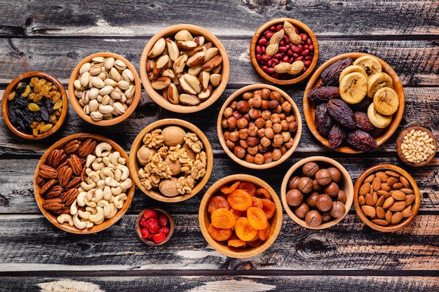 Various Nuts and dried fruits in wooden bowls top view