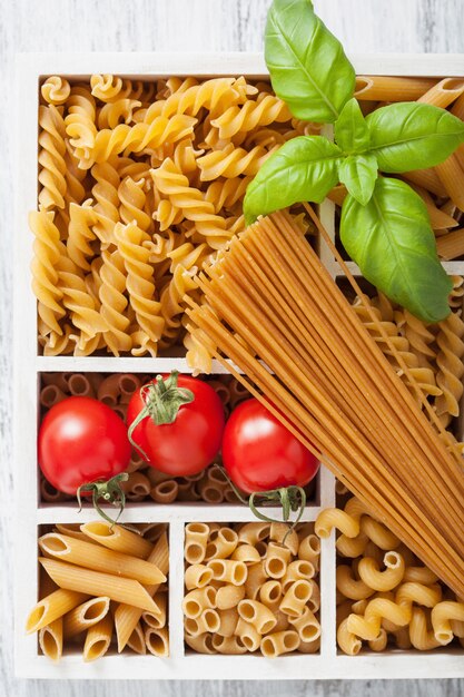 Various raw wholegrain pasta in white wooden box