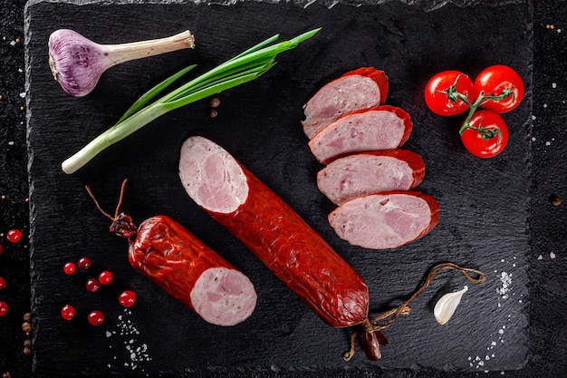 Various sausages and smoked products lie on a black board