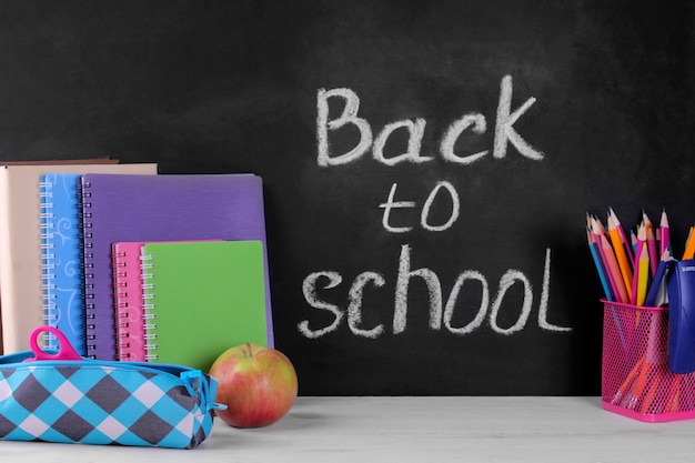 Various school supplies next to a blackboard