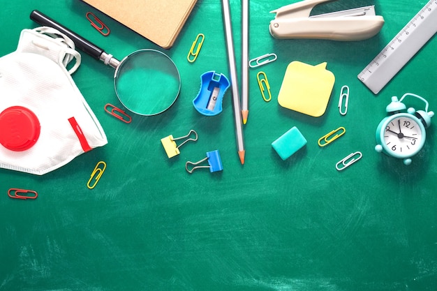 Various school supplies on a shabby green background in the form of a school board welcome to school...