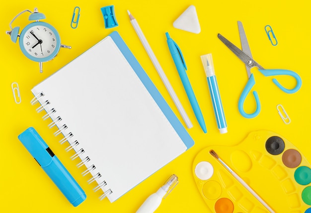 Various school supplies on vibrant yellow background. Copy space, top view