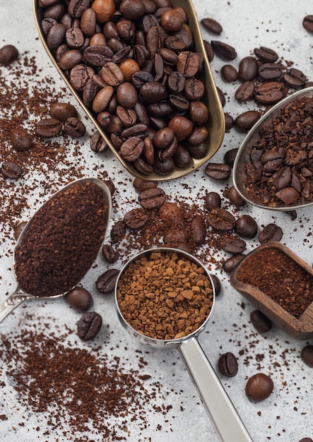 Various scoops with ground and bean coffee and freeze dried instant coffee granules on white background Top view