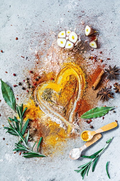 Various spice powders paprika curry coriander ginger dried onions and garlic turmeric cinnamon pepper anise and herbs rosemary bay leaf on gray background Indian and Asian cuisine