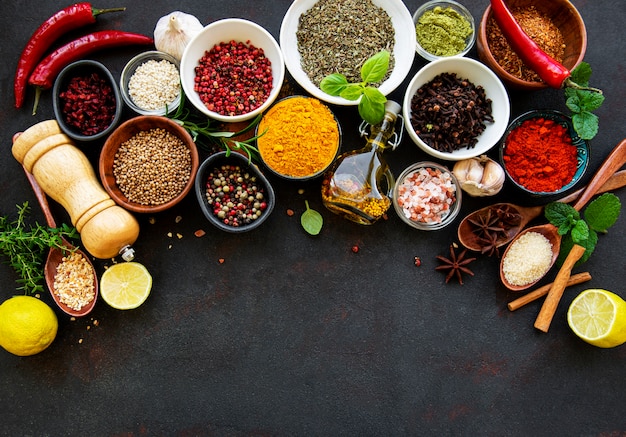 Various spices in a bowls on black concrete surface. Top view copy space.