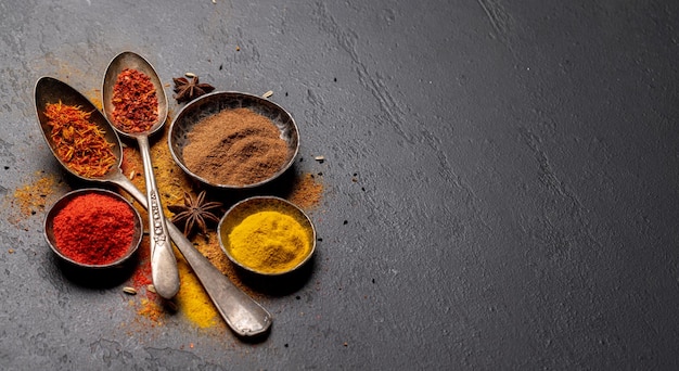 Various spices in bowls and spoons on stone table