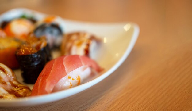 Various sushi in a white plate placed on a wooden table