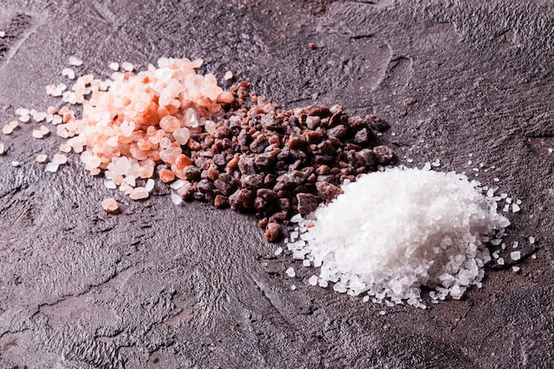 Various tupes of salts, pink Himalayas and black with sea salt on slate background