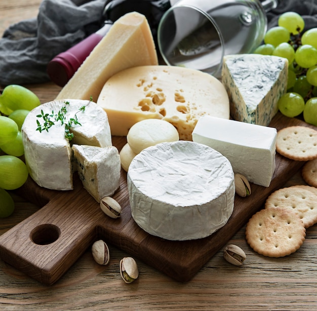 Various types of cheese, grapes and wine on a wooden table