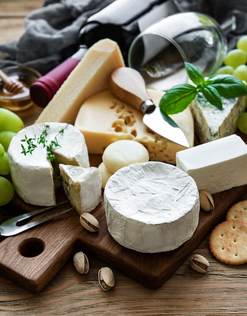 Various types of cheese, grapes and wine on a wooden table