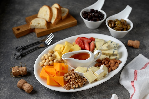 Various types of cheeses with olives, nuts, fruits and honey