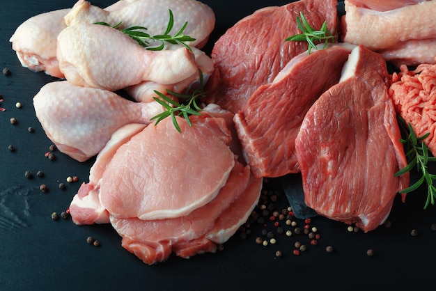 Various types of fresh meat pork beef turkey and chicken on a wooden black table