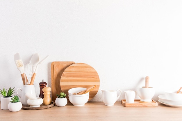 Various types of kitchen utensils on a wooden countertop at the textured white concrete wall Zero wasteenvironmentally friendly concept