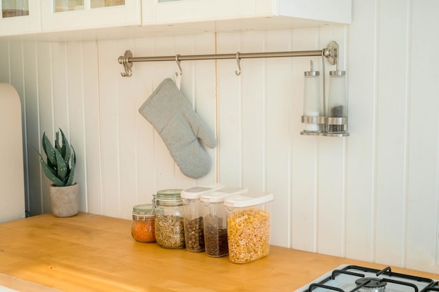 Various uncooked cereals, grains, beans and pasta for healthy cooking in glass jars on wooden table.