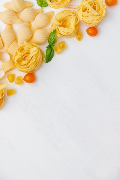 Various uncooked pasta on wooden background