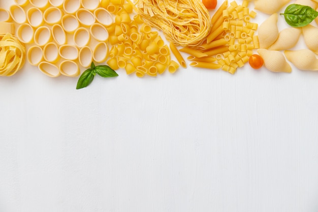 Various uncooked pasta on wooden background